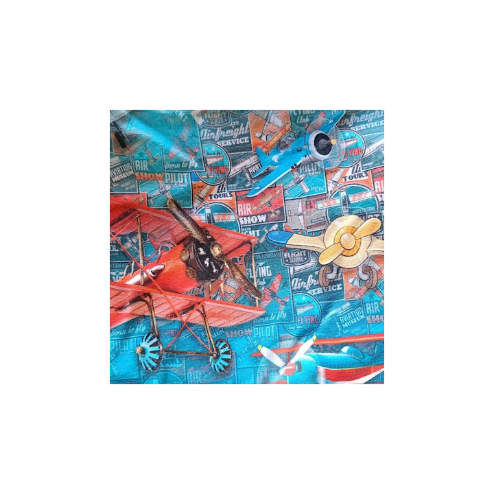 Primer plano del tejido estampado con aviones clásicos rojos y azules, hélices y tipografía retro sobre fondo turquesa.