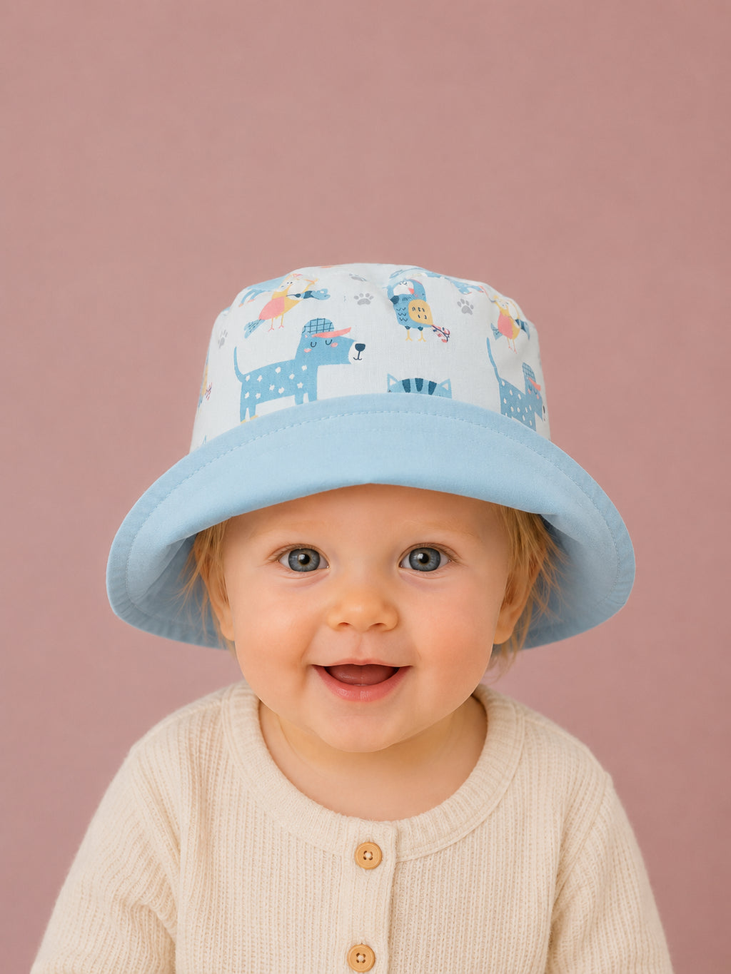 Bebé con gorrito de pescador reversible de tucanes y reverso azul cielo hecho a mano en algodón