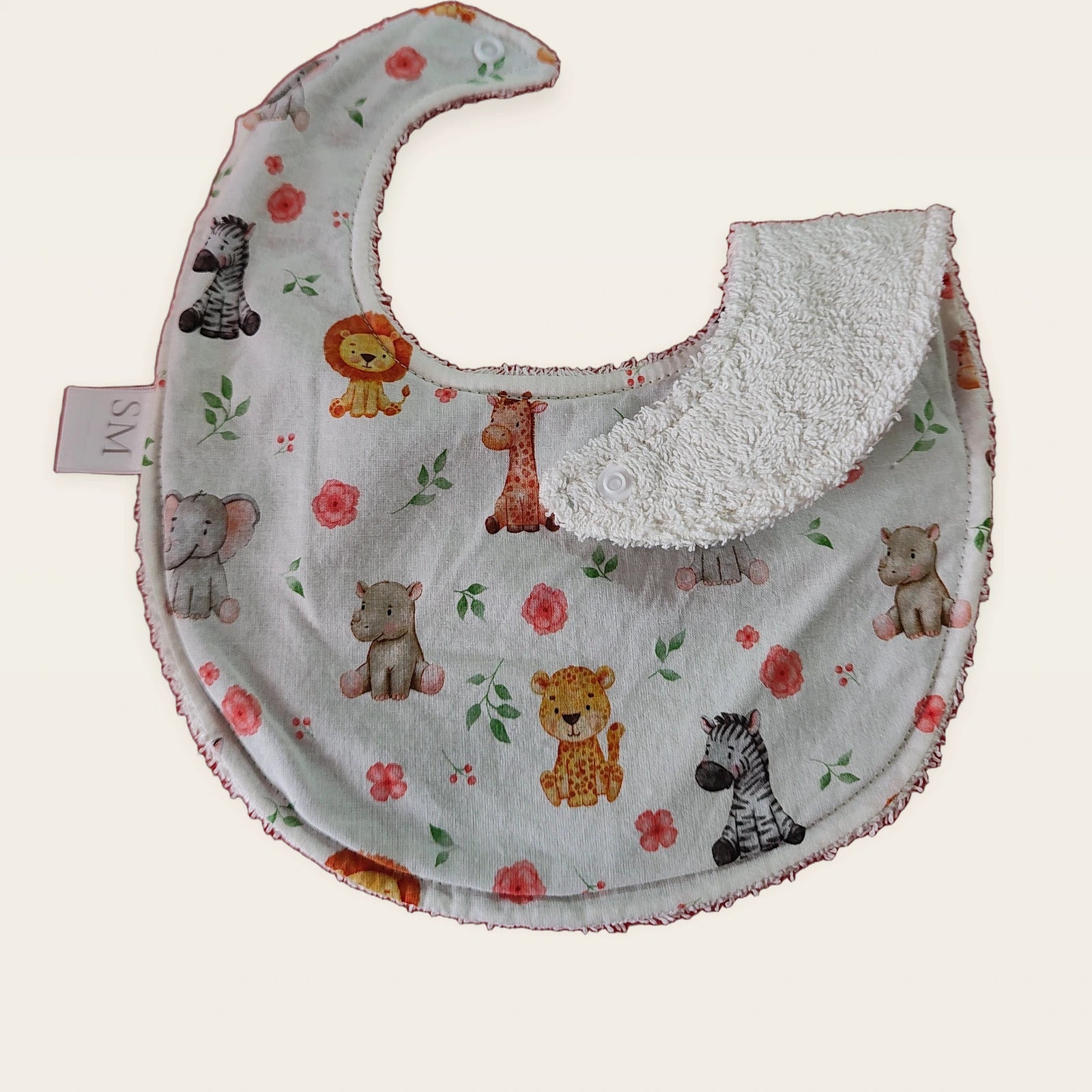 Babero impermeable 0–6 meses Animalitos de la sabana con una pata doblada para mostrar el rizo de algodón blanco roto