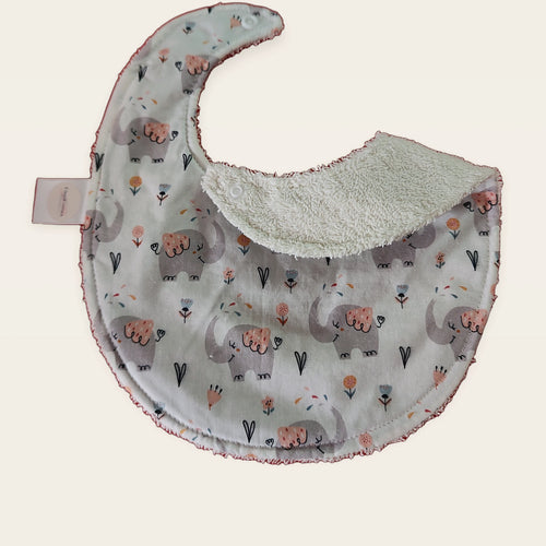 Babero impermeable 0–6 meses Cuquielefantes con una pata doblada para mostrar el rizo de algodón blanco roto