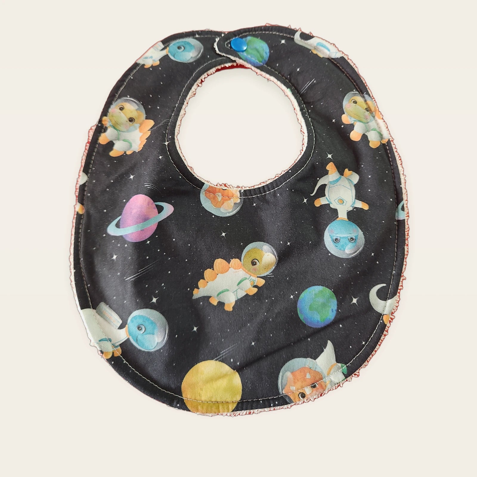Babero impermeable 0–6 meses Dinosaurios del espacio con rizo de algodón blanco roto, vista frontal