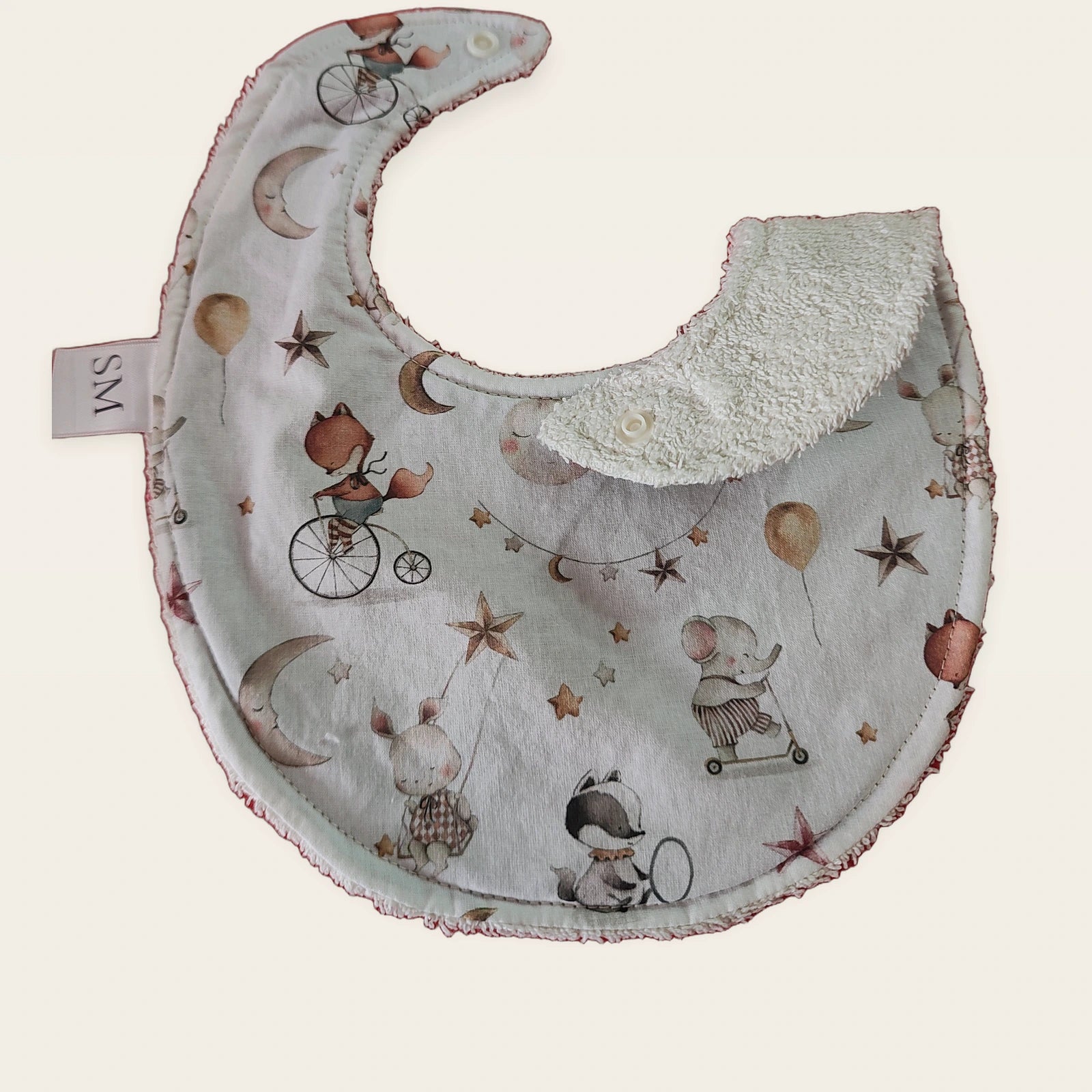 Babero impermeable 0–6 meses Elefantitos, luna y estrellas con una pata doblada para mostrar el rizo de algodón blanco roto