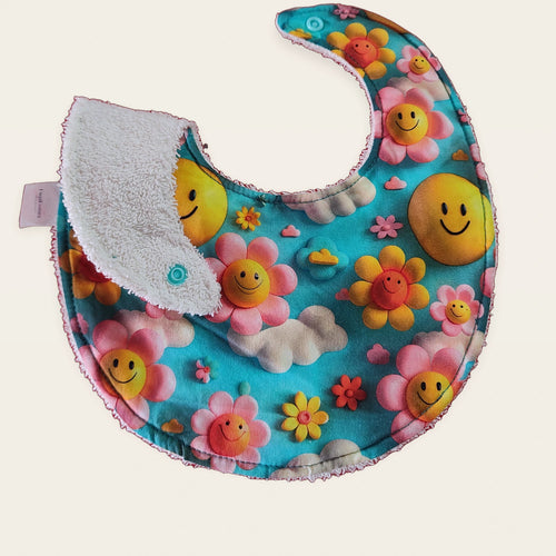 Babero impermeable 0–6 meses Flores 3D con una pata doblada para mostrar el rizo de algodón blanco roto