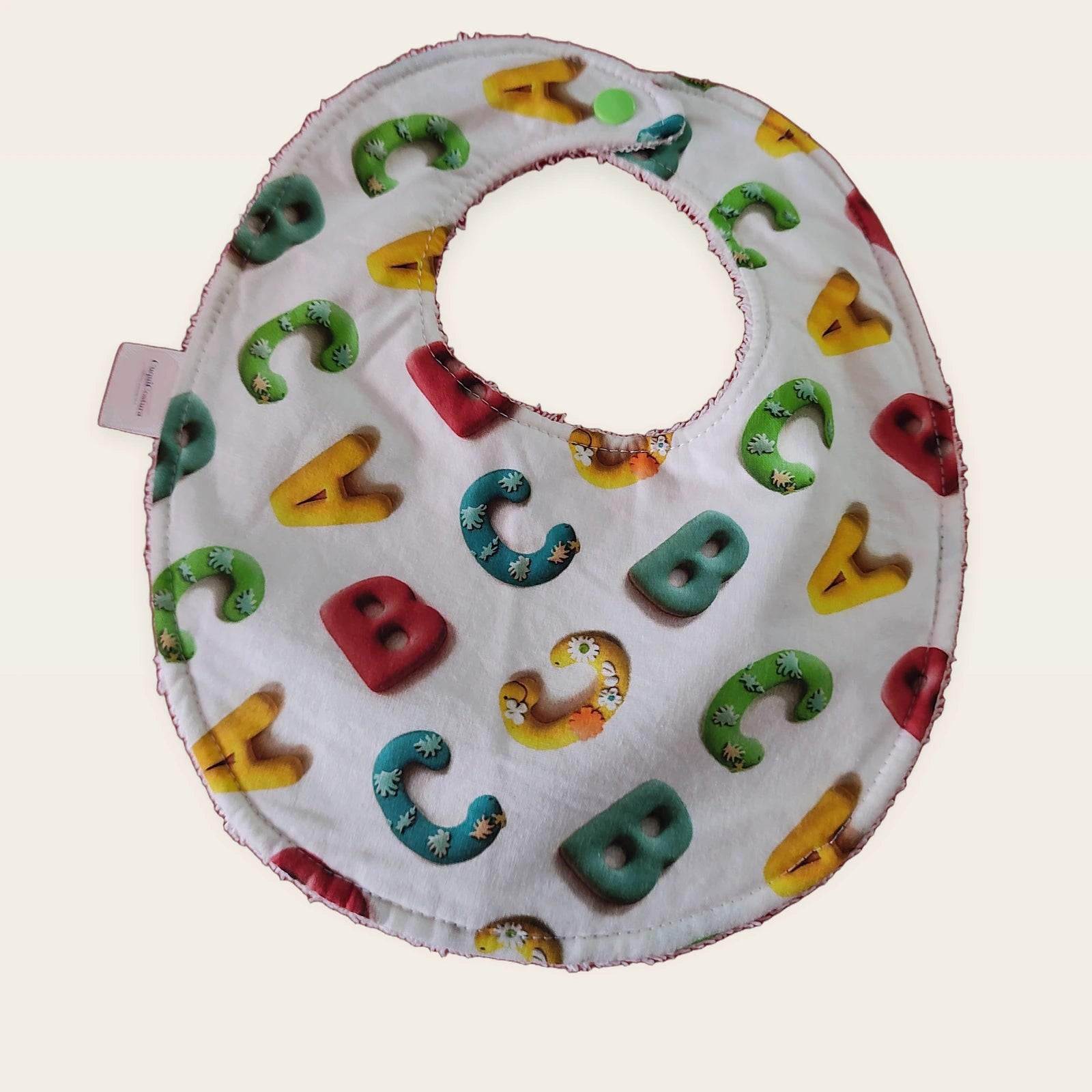 Babero impermeable 0–6 meses Letras de colores con rizo de algodón blanco roto, vista frontal