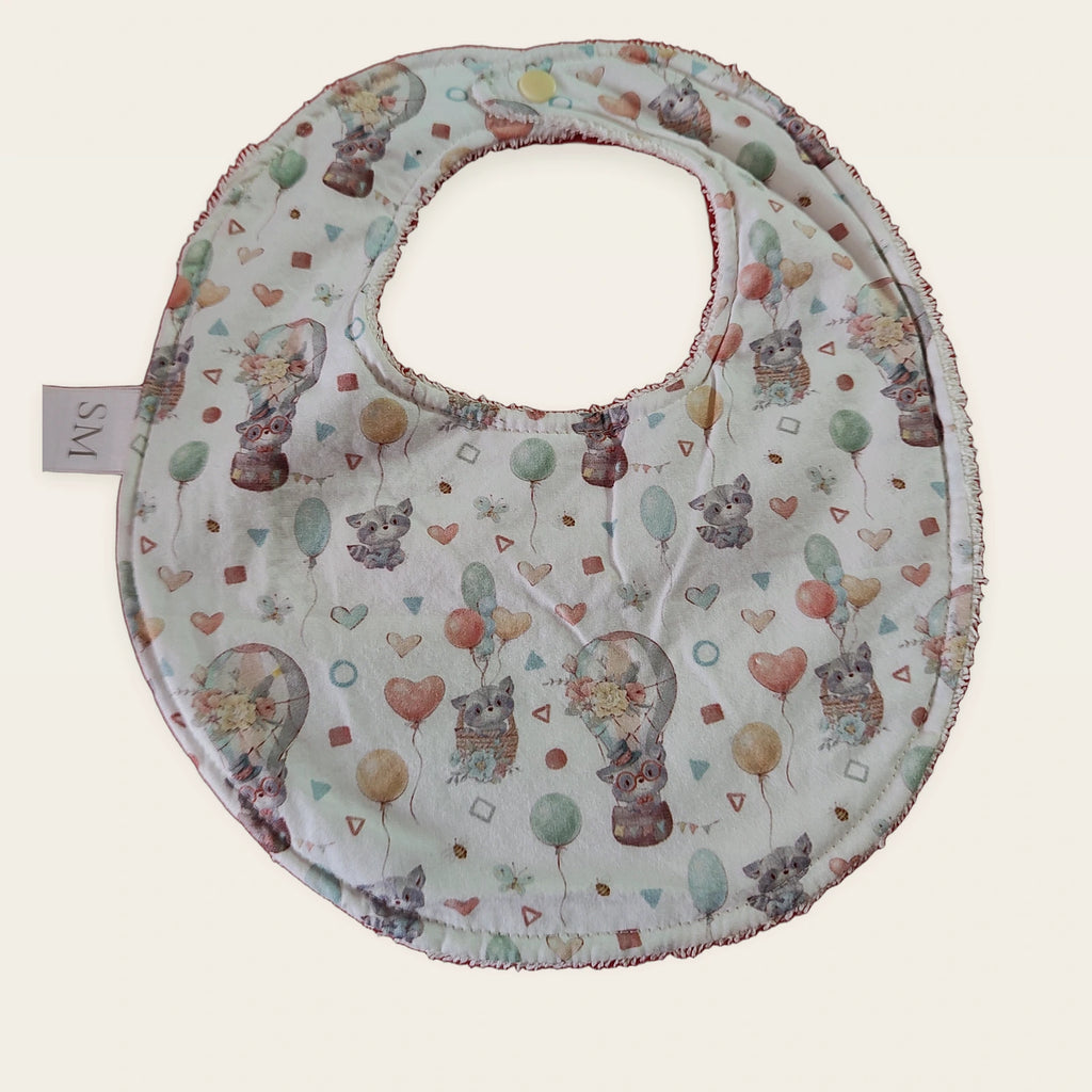 Babero impermeable 0–6 meses Mapaches con globos con rizo de algodón blanco roto, vista frontal
