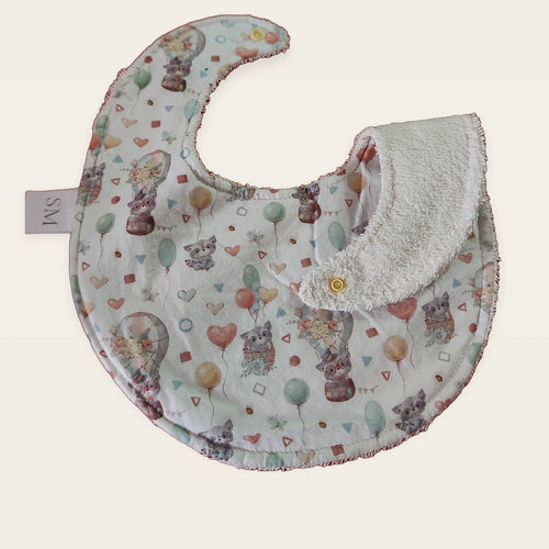 Babero impermeable 0–6 meses Mapaches con globos con una pata doblada para mostrar el rizo de algodón blanco roto