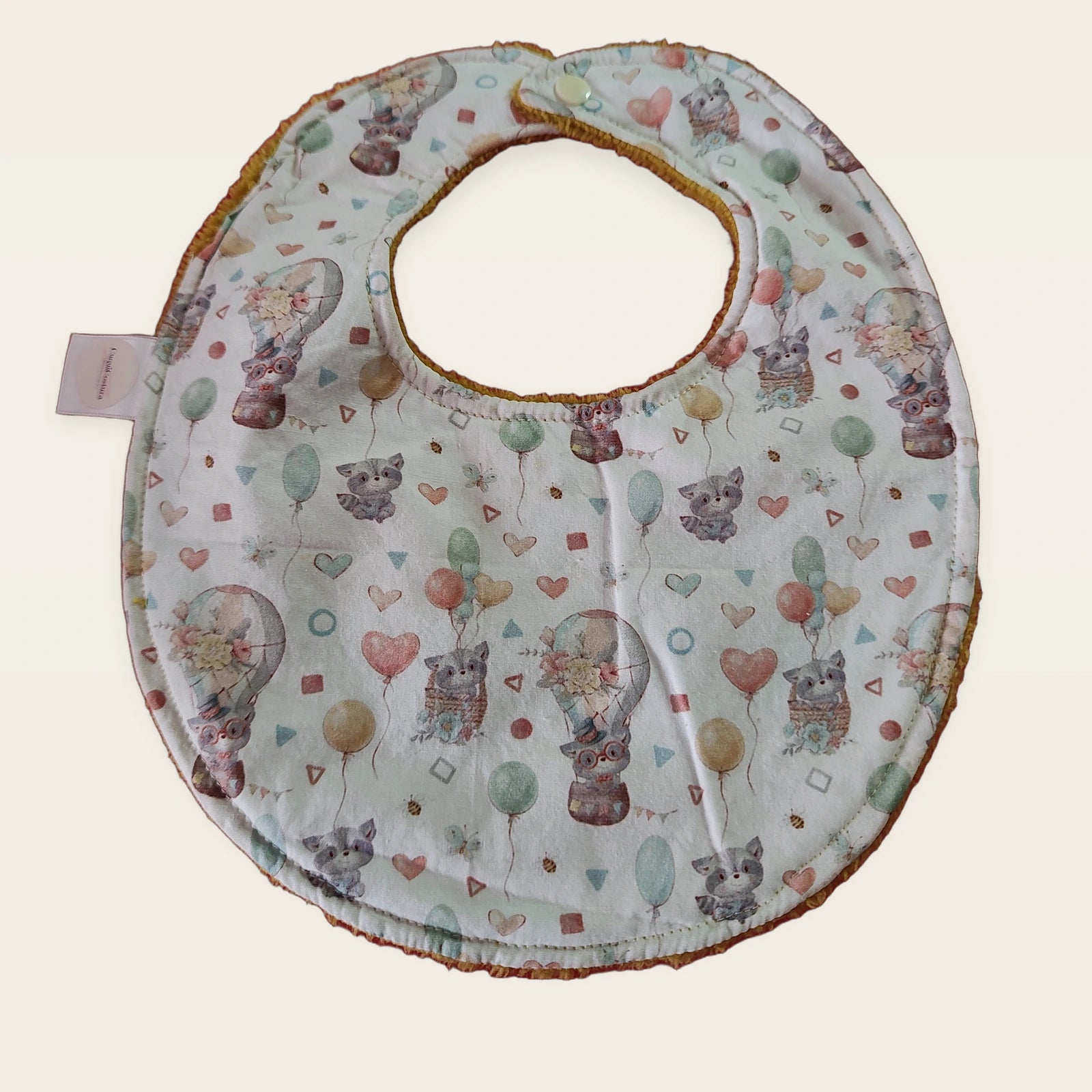 Babero impermeable 0–6 meses Mapaches con globos con rizo de bambú mostaza, vista frontal