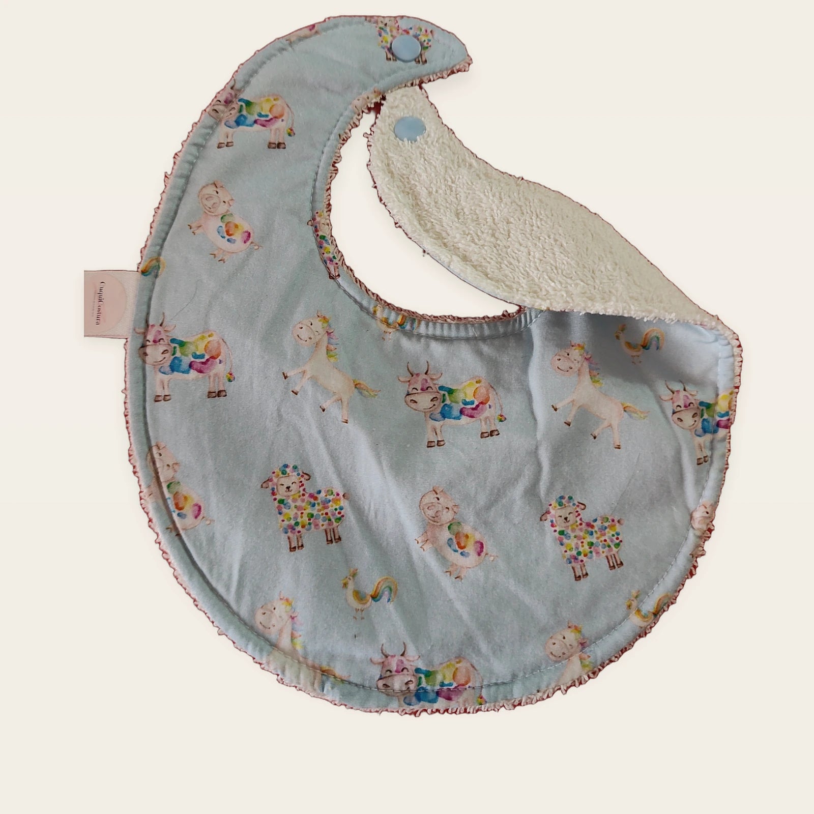 Babero impermeable 0–6 meses Ovejitas arcoíris con una pata doblada para mostrar el rizo de algodón blanco roto