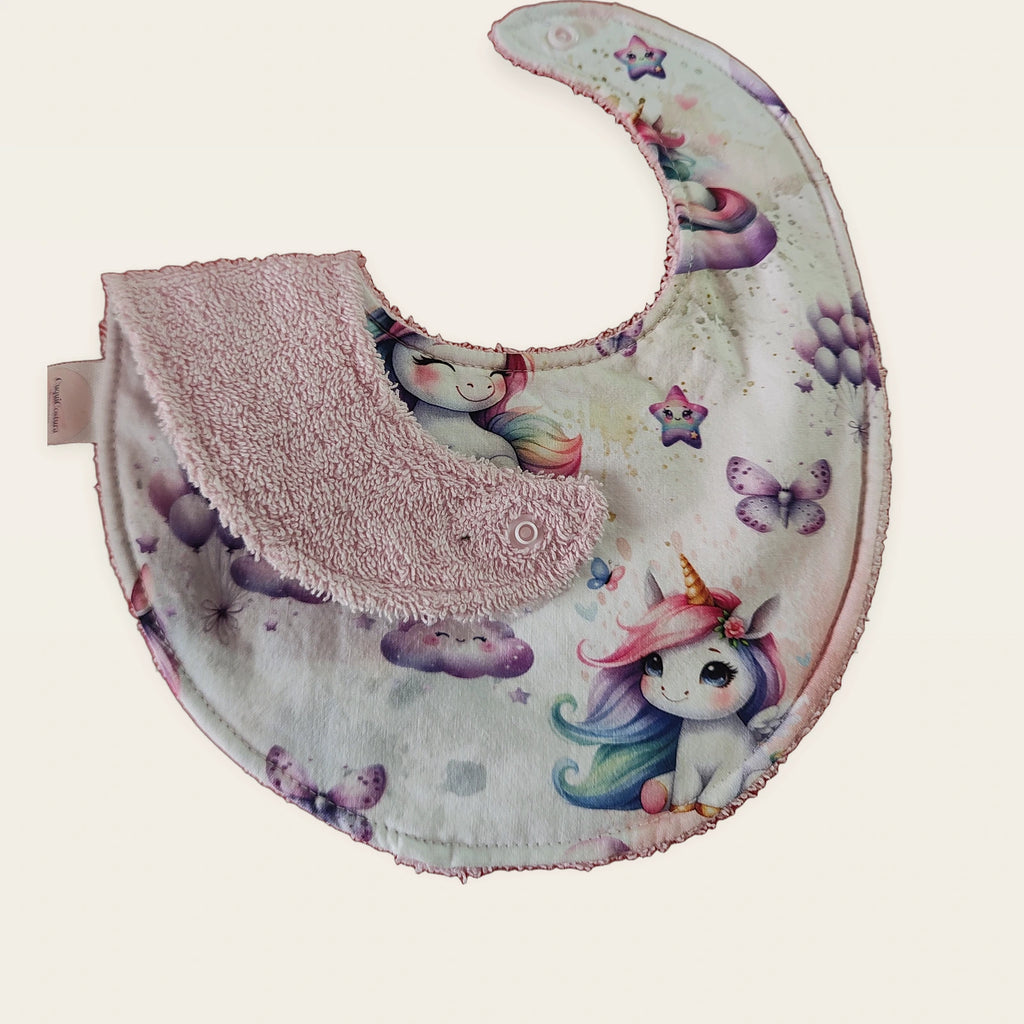 Babero impermeable 0–6 meses Unicornio mágico con una pata doblada para mostrar el rizo de algodón blanco roto