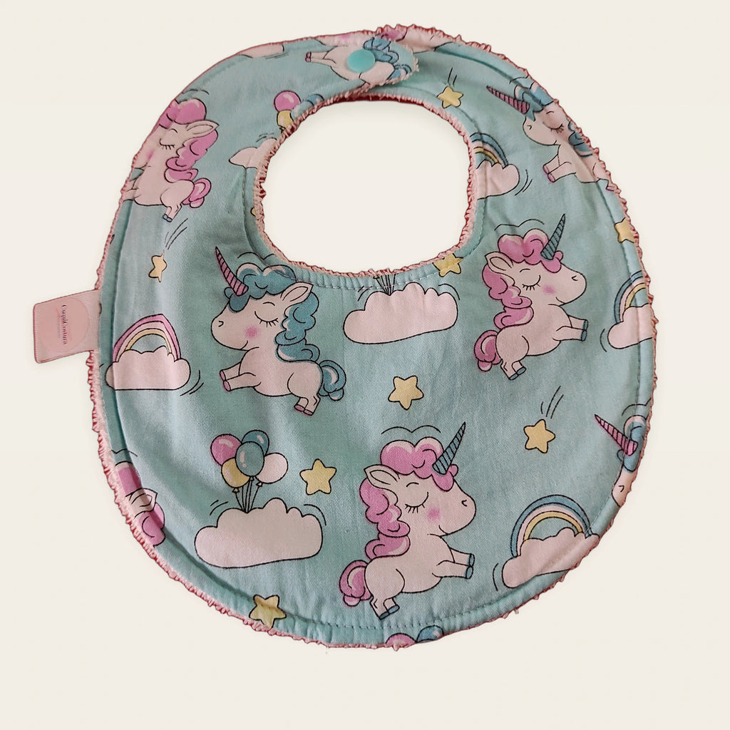 Babero impermeable 0–6 meses Unicornios entre nubes con rizo de algodón blanco roto, vista frontal