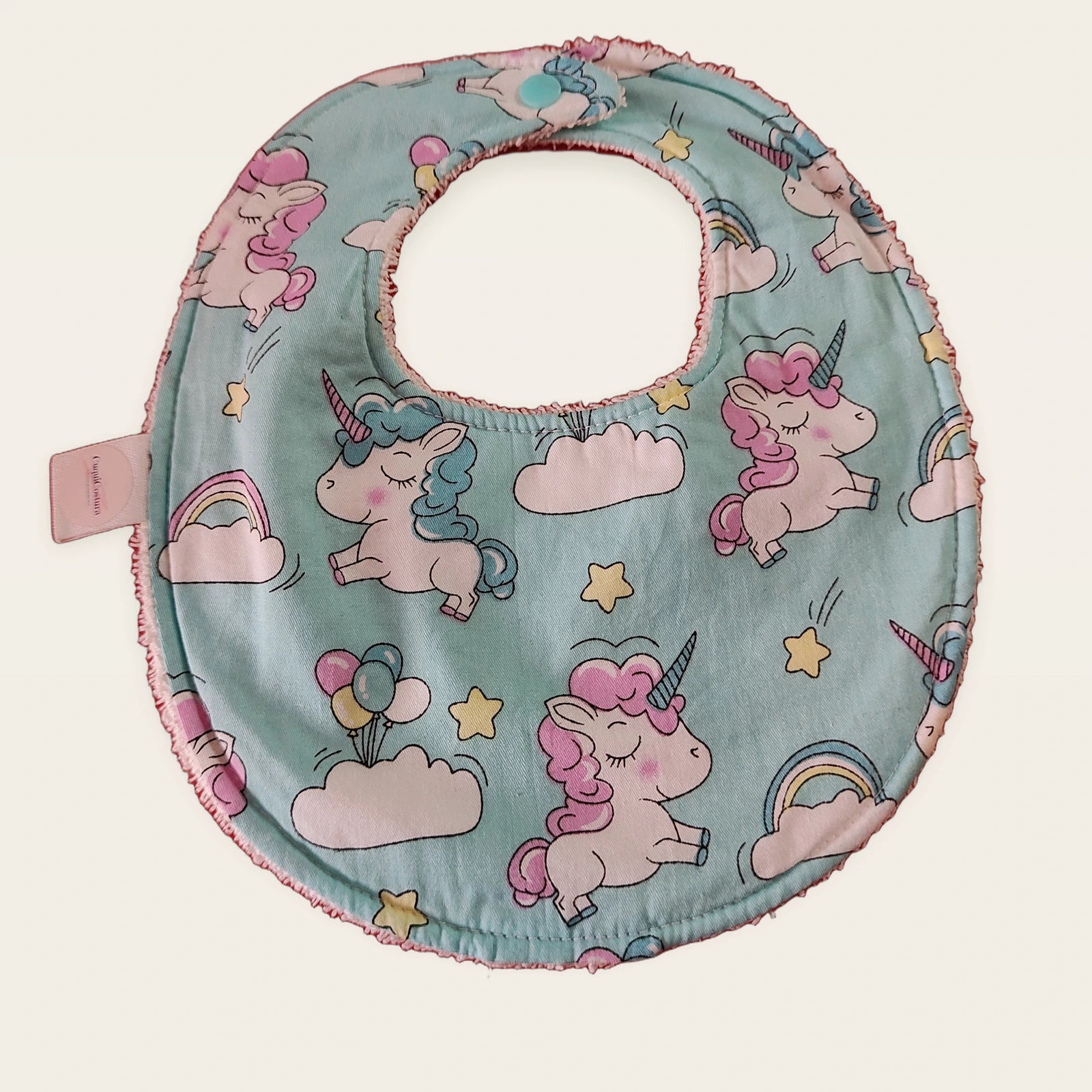 Babero impermeable 0–6 meses Unicornios entre nubes con rizo de algodón blanco roto, vista frontal