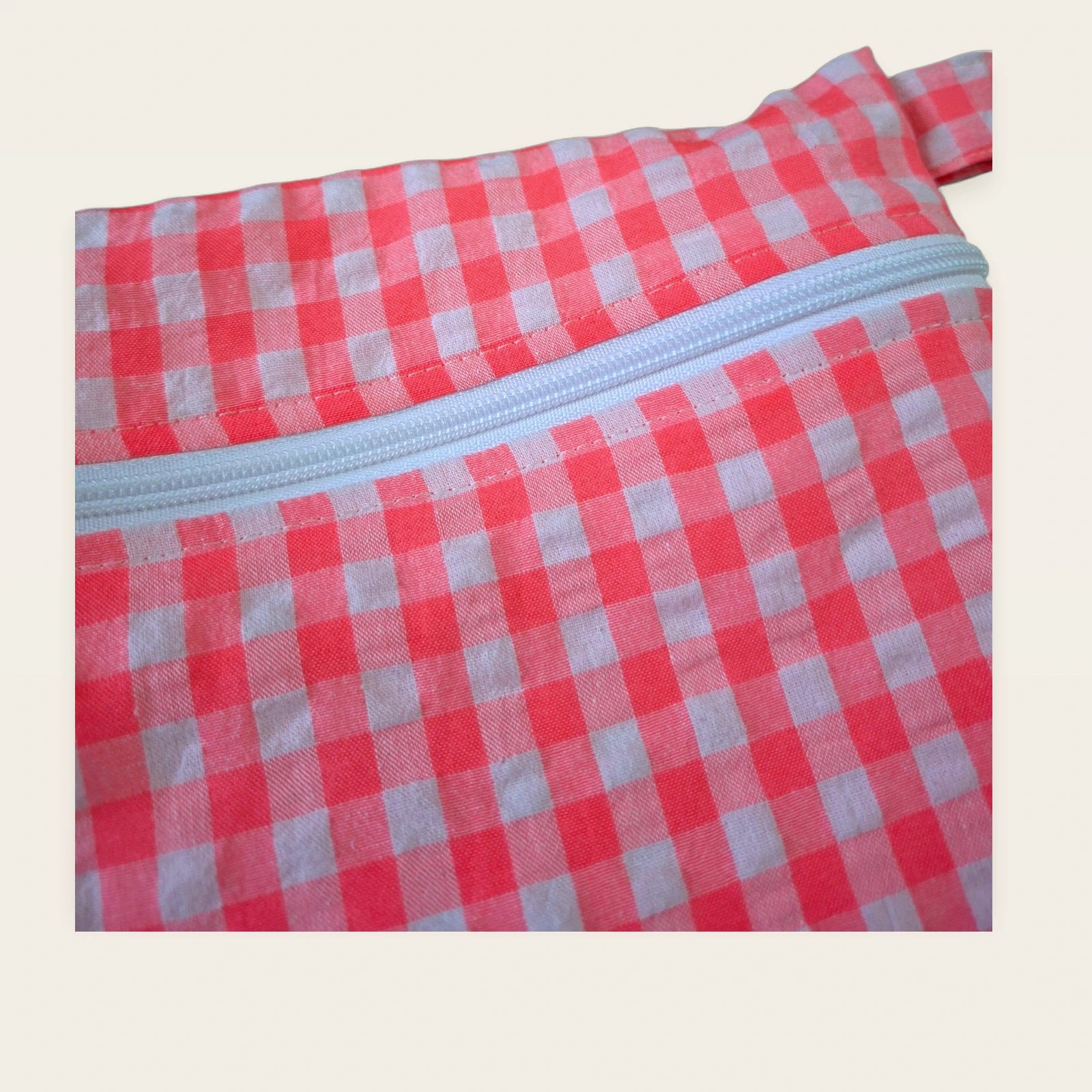 Detalle frontal de la cremallera blanca de la bolsa impermeable Vichy rosa flúor
