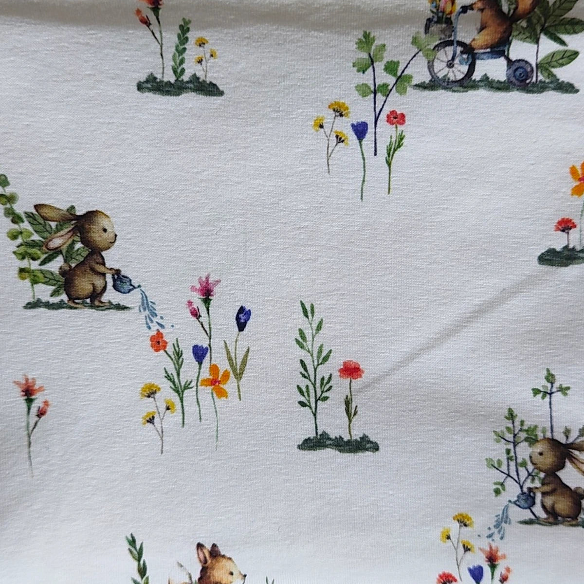 Detalle del estampado de conejitos regando en el tejido de punto de una braga de cuello infantil