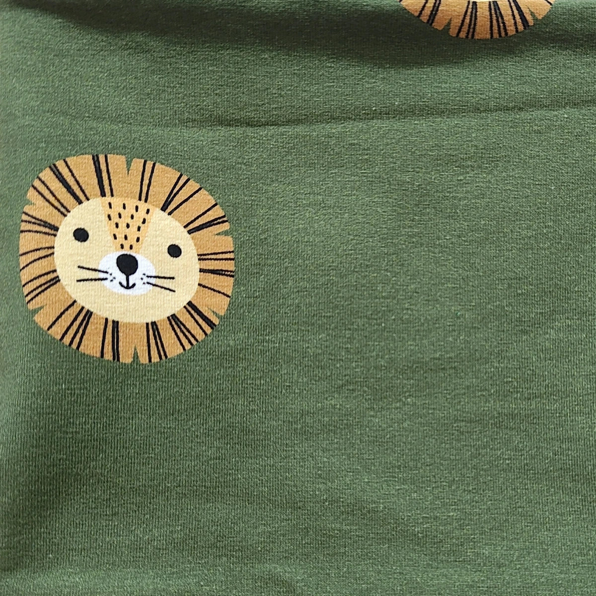 Detalle del estampado de leones en tonos verdes en el tejido de punto de una braga de cuello infantil
