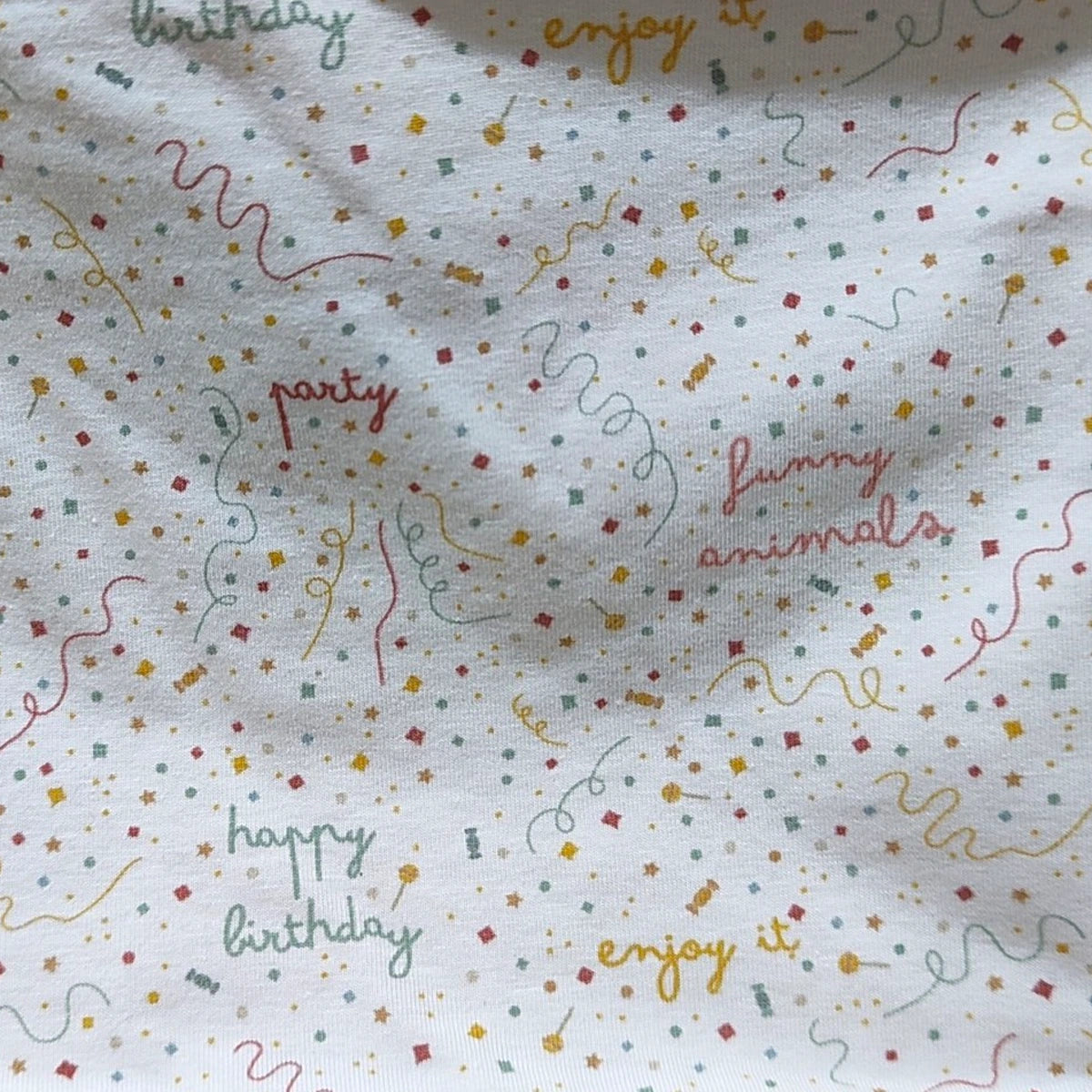 Detalle del estampado de motivos de fiesta en el tejido de punto de una braga de cuello infantil